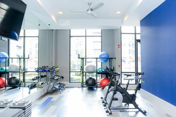 A gym with a lot of exercise equipment and a large window